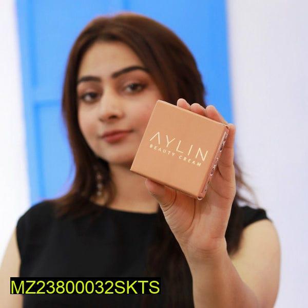 Woman holding a box of Aylin Beauty Cream against a blurred background
